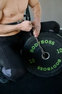 Athletic man setting up weights with chains for strength training indoors.