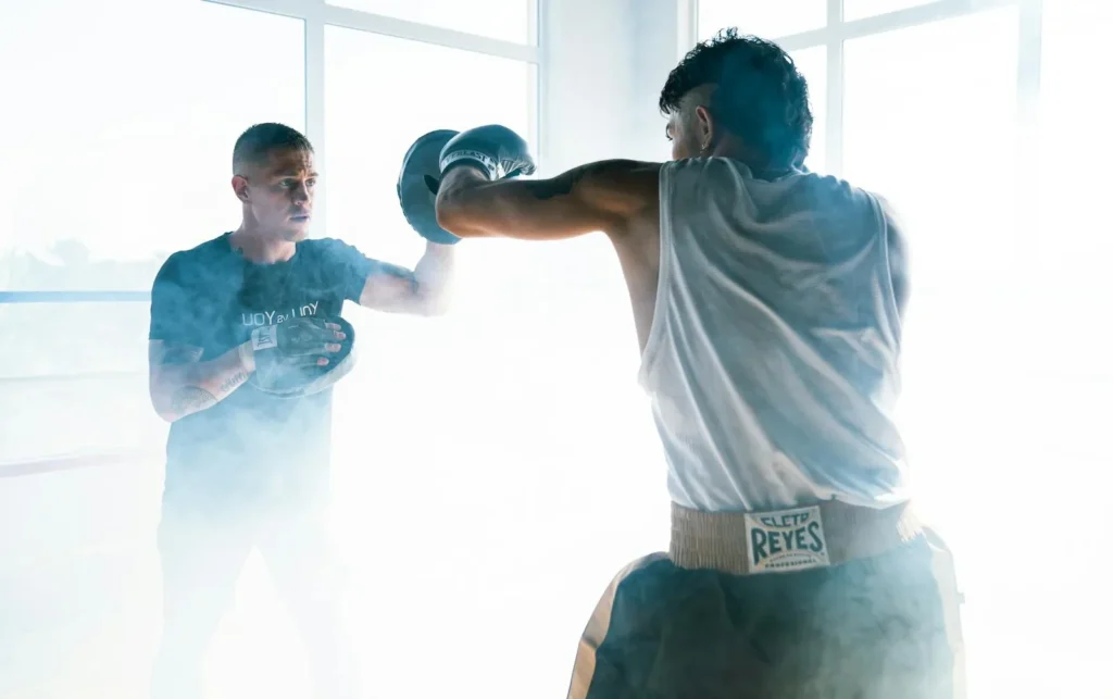 Two men engage in a dynamic boxing training session, featuring punching techniques.