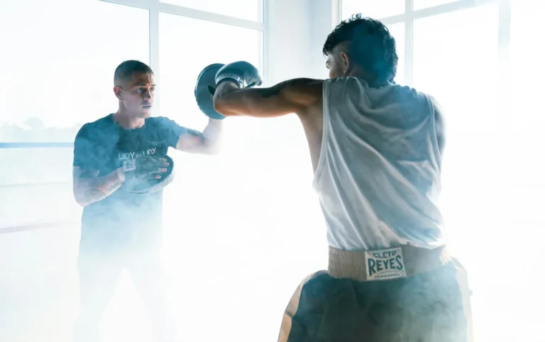 Two men engage in a dynamic boxing training session, featuring punching techniques.