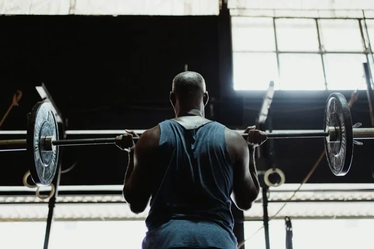 A muscular man lifting a barbell indoors, showcasing strength and fitness.