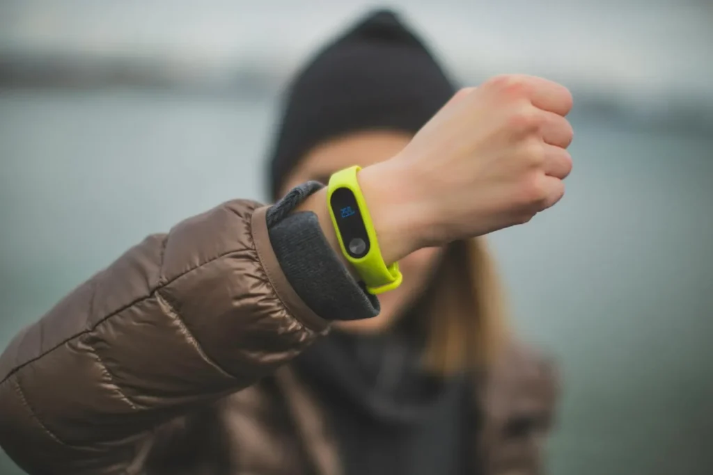 Close-up of a person holding up a fitness tracker, emphasizing technology and active lifestyle.