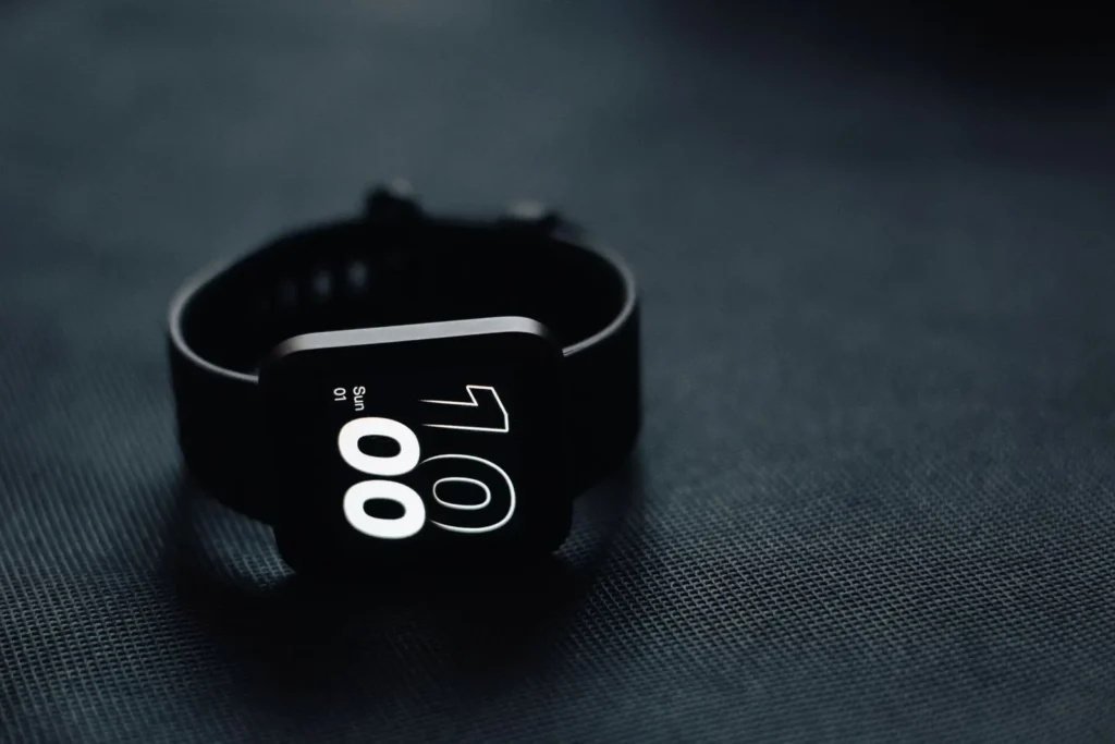 Modern smartwatch displaying time on a sleek dark gray surface, perfect for tech enthusiasts.