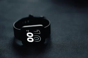 Modern smartwatch displaying time on a sleek dark gray surface, perfect for tech enthusiasts.
